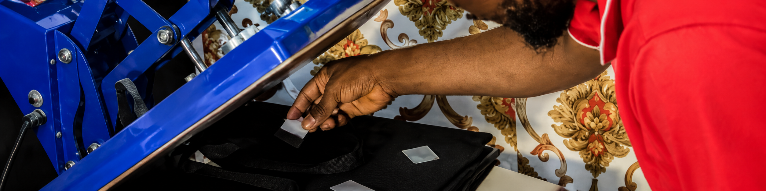 Close-up of a heat press machine applying a label or logo detail onto a black bag during custom OEM bag production.