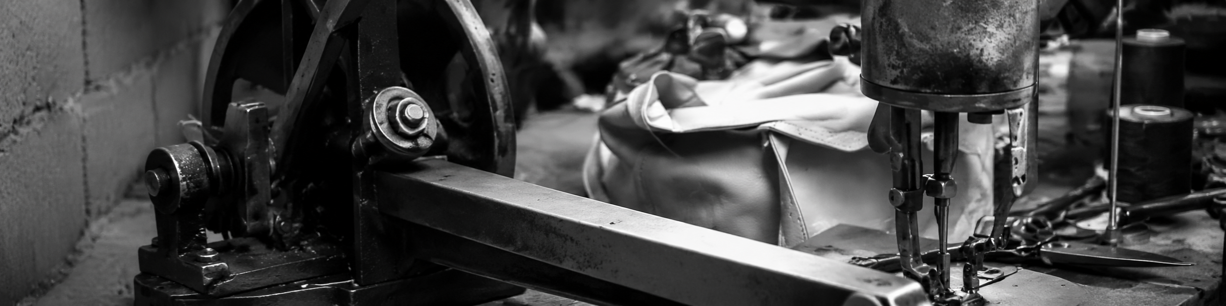 Black and white close-up of an industrial sewing machine in a bag manufacturing workshop, showing OEM bag production equipment and stitching process.